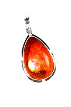 A silver pendant with a gemstone with a design that appears like a bright setting sun in orange-red color, on white studio background.