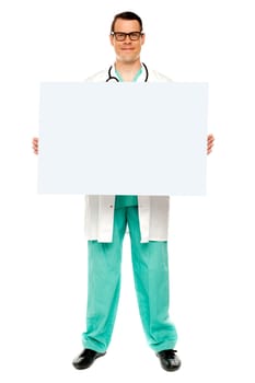 Handsome male doctor displaying white advertising board, full length shot