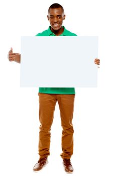 Full length portrait of casual young guy pointing towards placard