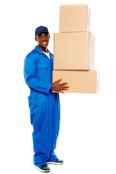 Smiling young delivery boy holding cardboard boxes isolated on white background