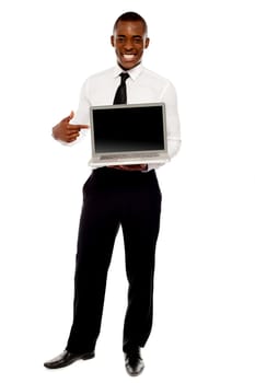 Cheerful male executive pointing at open laptop, full length portrait