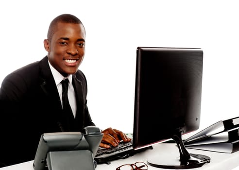 Smiling young corporate man using computer looking at camera
