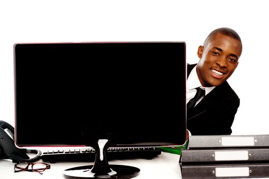 Businessman peeping from behind lcd monitor and enjoying himself during work hours