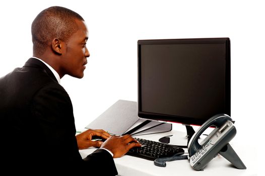 Male executive typing and looking at lcd screen working in office
