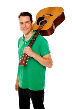 Cheerful handsome casual man with guitar on shoulders looking at camera