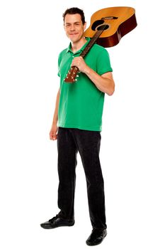 Casual music lover carrying guitar on his shoulders, full length portrait