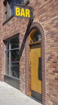 a brick building with a bar sign over a wood door.