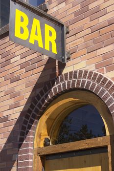 a brick building with a bar sign over a wood door.