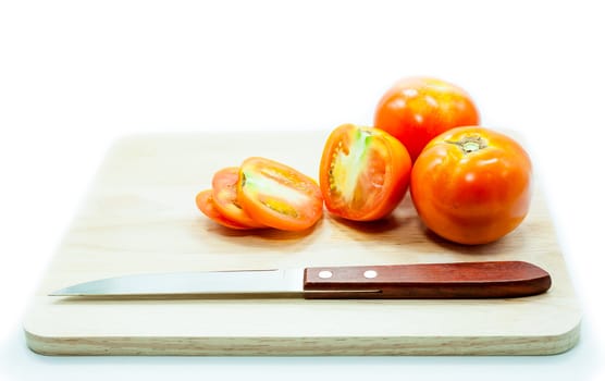 Tomato and knife on cutting board isolated on a white background