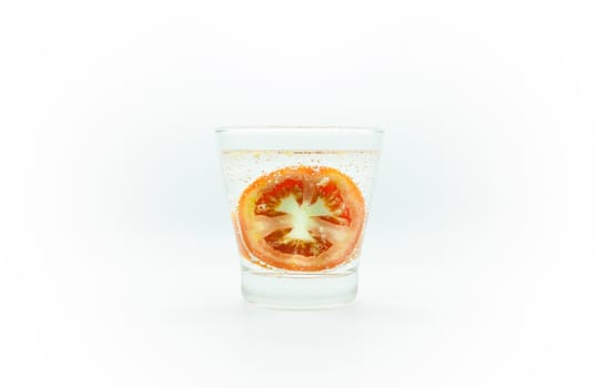 Tomato slice in soda water in glass isolate on white background