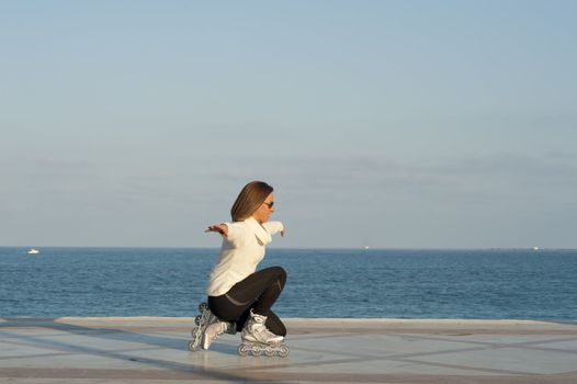 Blond woman skilfully rollerblading along a beach promenade