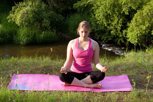 Pretty young woman doing Yoga at sunset.