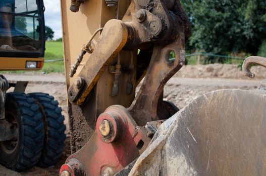 closeup of a shovel with excavator in the background