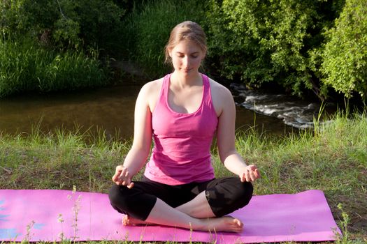 Pretty young woman doing Yoga at sunset.