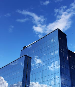 Modern office building reflecting blue sky white clouds