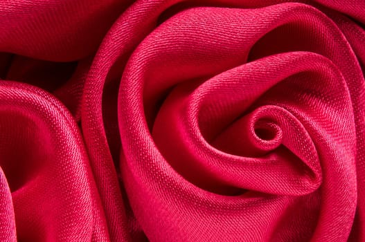 Close up of shiny red fabric rose shaped flower.