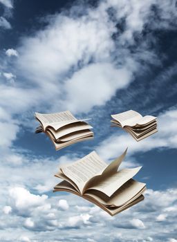 Three open books flying on blue sky background fantasy