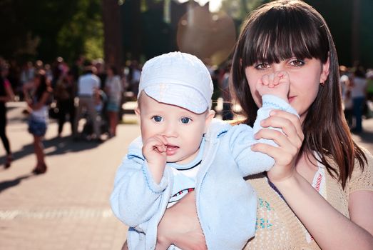 Young charming mother with her son in her arms for a walk in a park.