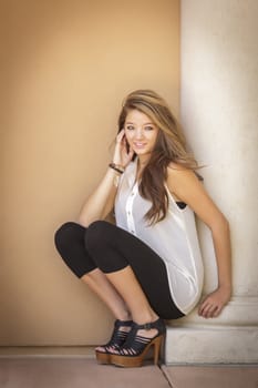 Attractive Mixed Race Girl Portrait Sitting Outdoors Against Wall.