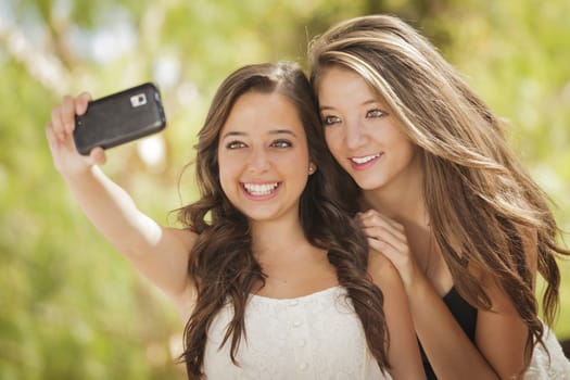 Two Attractive Mixed Race Girlfriends Taking Self Portrait with Their Phone Camera Outdoors.