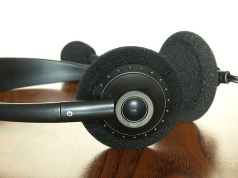 Black  headset on a wooden table taken closeup.