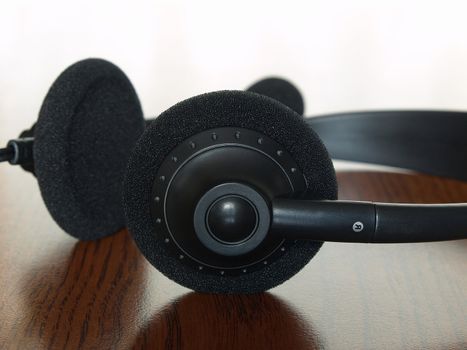 Black  headset on a wooden table taken closeup.