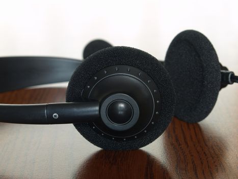 Black  headset on a wooden table taken closeup.