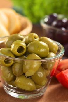 Preparing a fresh salad. Green olives with tomatoes, black olives, lettuce and bread (Selective Focus, Focus on the green olives on the top) 