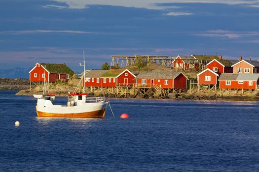 Red fishing rorbu huts and fishing boat in town of Reine on Lofoten islands