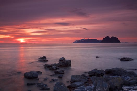 Midnight sun on Lofoten islands in Norway with island of Moskenesoya on the horizon