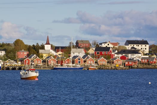 Picturesque town of Reine on Lofoten islands in Norway with fishing boats and typical red rorbu houses by the fjord