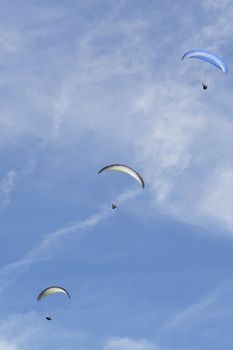 Three para gliders against a blue sky