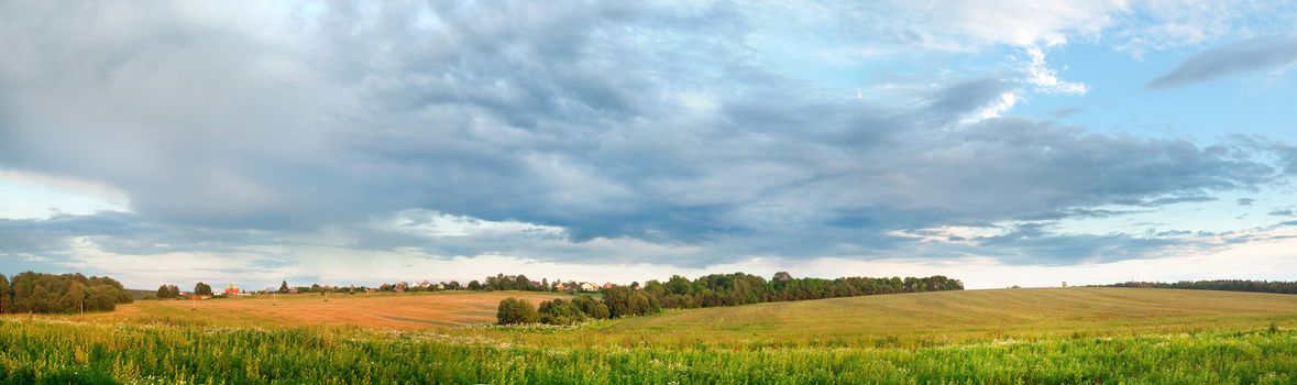 Countryside landscape panorama with green field and small village