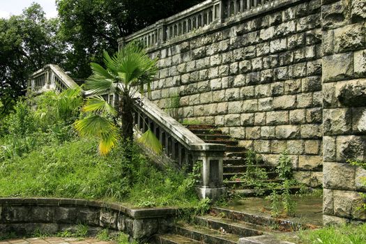 ancient stages of tumbledown bridge surrounded green vegetation