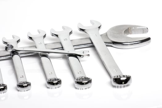 Some steel wrenches of different sizes on a white background