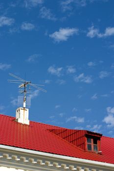 brightly red roof with a dormer on a background blue sky