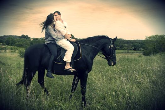 beautiful black stallion in a field with young couple, vintage effect