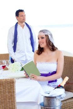 Couple in wedding day with woman reading book on banquet table