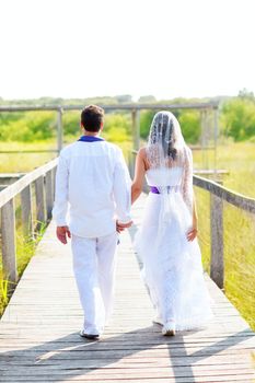 Couple happy in wedding day walking in outdoor rear view