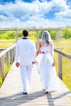 Couple happy in wedding day walking in outdoor rear view