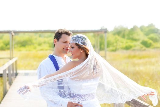 Couple in wedding day outdoor with wind on veil