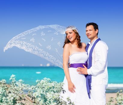 Couple in wedding day on beach sea with wind on veil