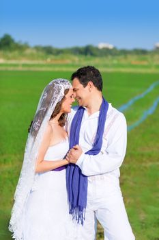 Couple in wedding day hug in outdoor green meadow