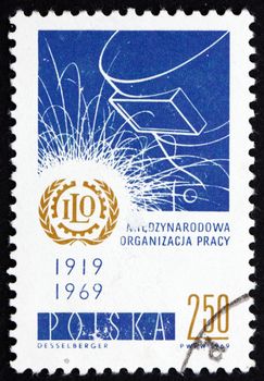 POLAND - CIRCA 1969: a stamp printed in the Poland shows ILO Emblem and Welder's Mask, 50th Anniversary of International Labor Organization, circa 1969