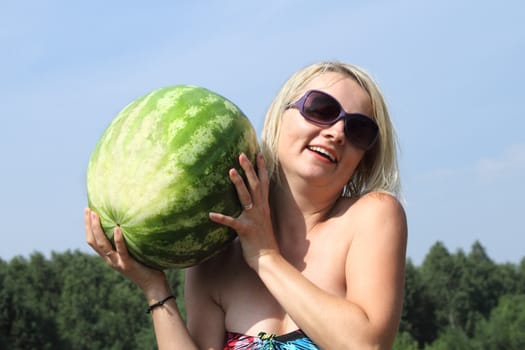 The smiling woman with the big watermelon on a background of the sky