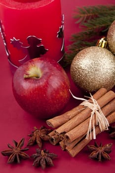 christmas decoration aromatic red apple, cinnamon, anise and tree on red background