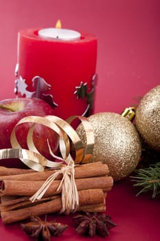 christmas decoration aromatic red apple, cinnamon, anise and tree on red background