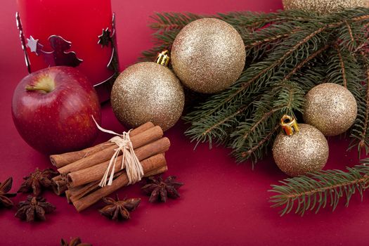 christmas decoration aromatic red apple, cinnamon, anise and tree on red background