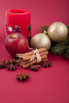 christmas decoration aromatic red apple, cinnamon, anise and tree on red background