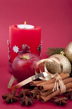 christmas decoration aromatic red apple, cinnamon, anise and tree on red background